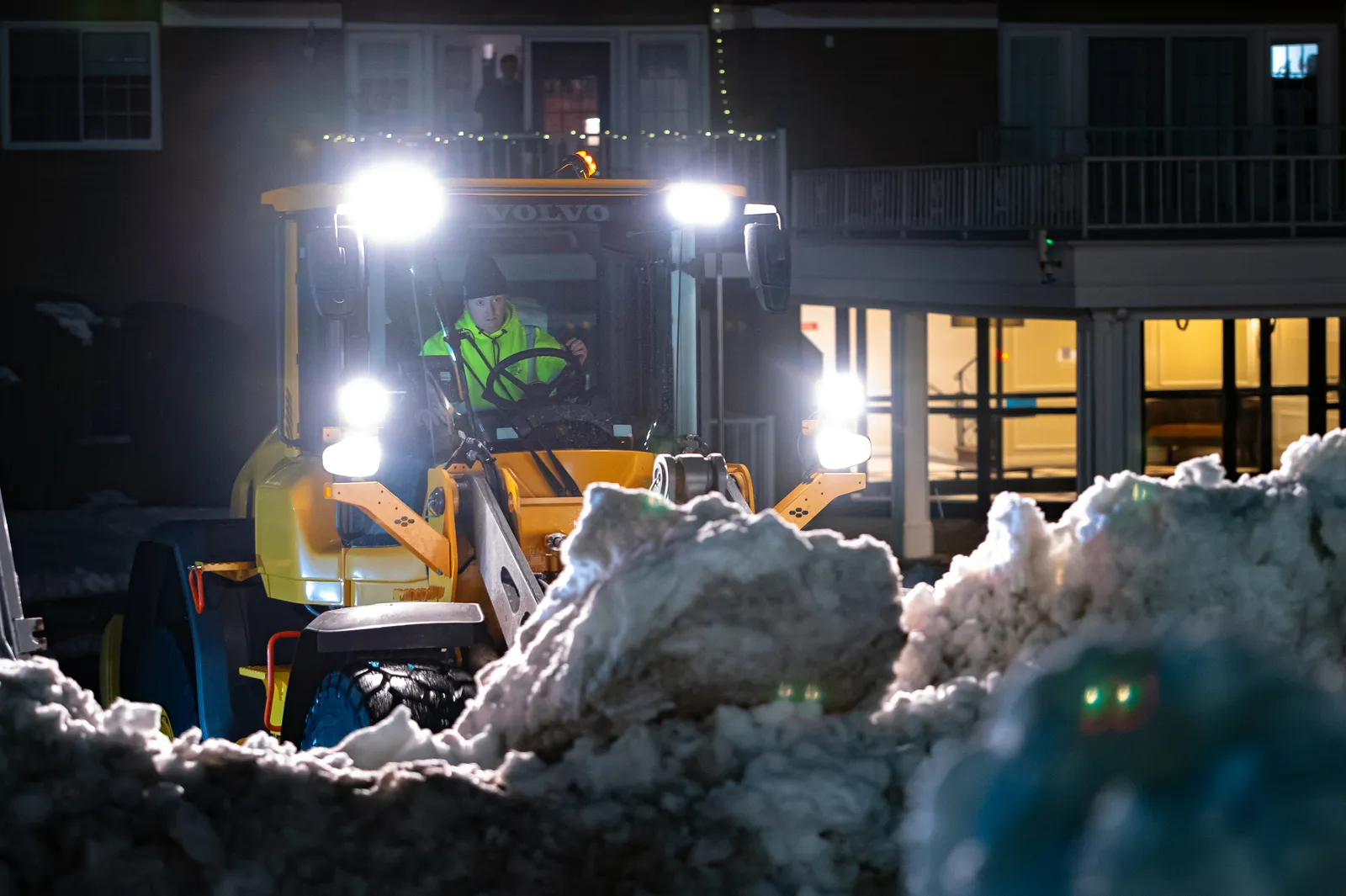 A Coastal Corp operator runs a wheel loader under work lights during an overnight snow-clearing job.